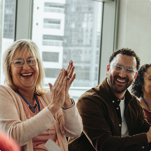 Smiling and clapping employees at a corporate event
